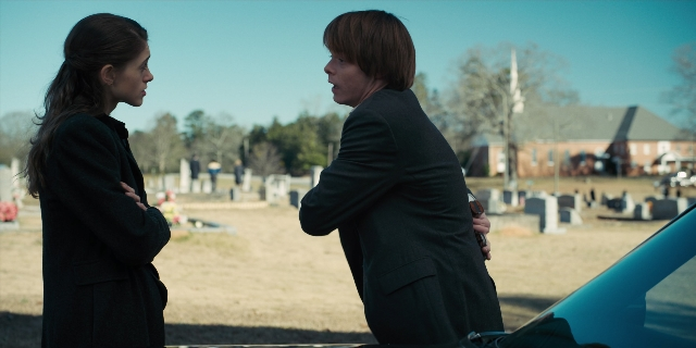 Wide shot frame from Stranger Things — standing, dialogue, car