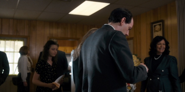 Wide shot frame from Stranger Things — standing, room, suit