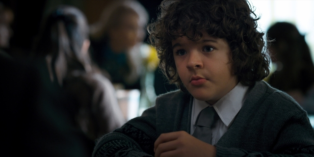 Medium shot frame from Stranger Things — sitting, suit, tie
