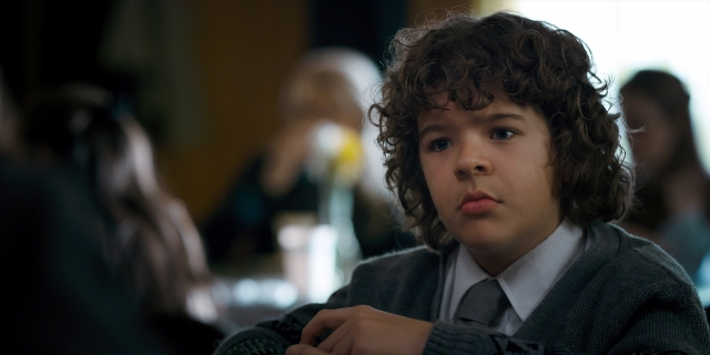 Medium shot frame from Stranger Things — sitting, table, suit