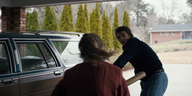 Wide shot frame from Stranger Things — standing, car, person