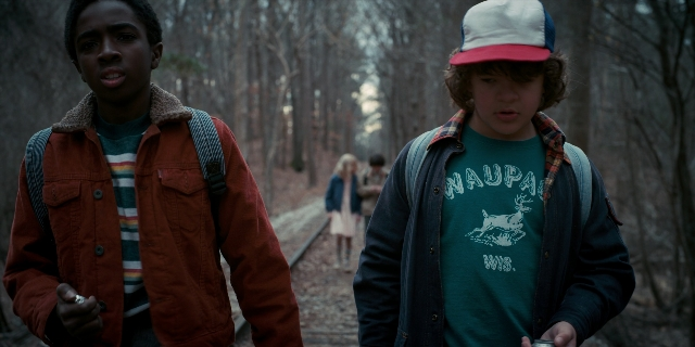 Wide shot frame from Stranger Things — walking, hat, hand
