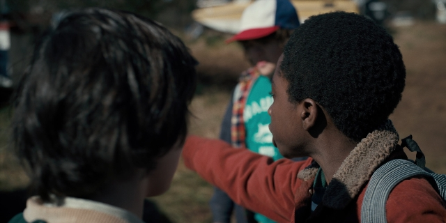 Wide shot frame from Stranger Things — standing, dialogue, hat