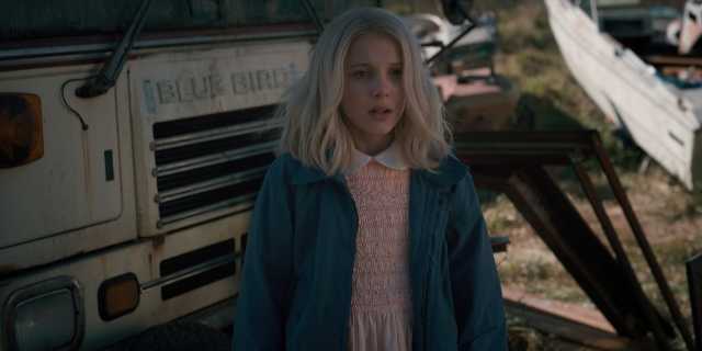 Wide shot frame from Stranger Things — standing, dress, hair