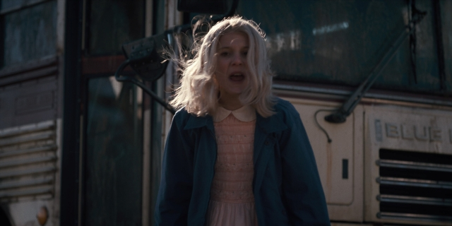 Wide shot frame from Stranger Things — standing, dress, bus