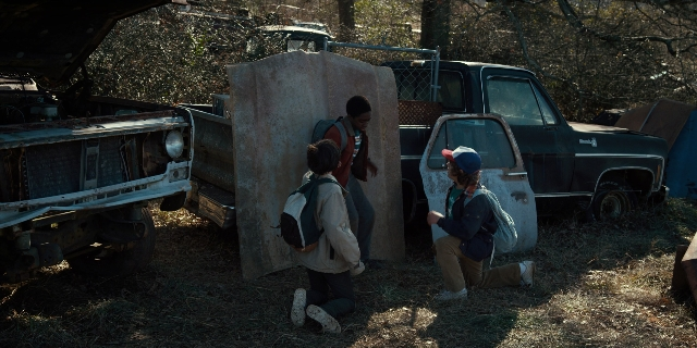 Wide shot frame from Stranger Things — standing, truck, wheel