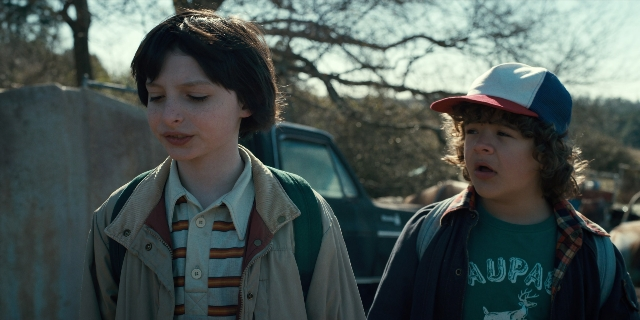 Wide shot frame from Stranger Things — standing, dialogue, street