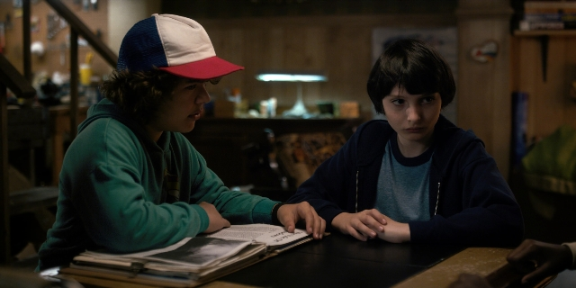 Wide shot frame from Stranger Things — sitting, book, room