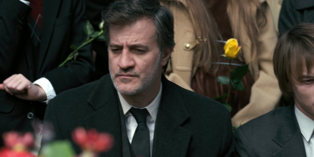 Medium shot frame from Stranger Things — sitting, suit, tie