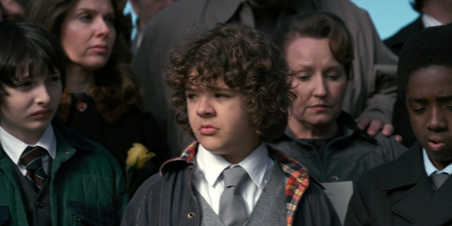 Wide shot frame from Stranger Things — standing, coat, suit
