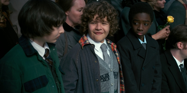 Wide shot frame from Stranger Things — standing, hand, suit
