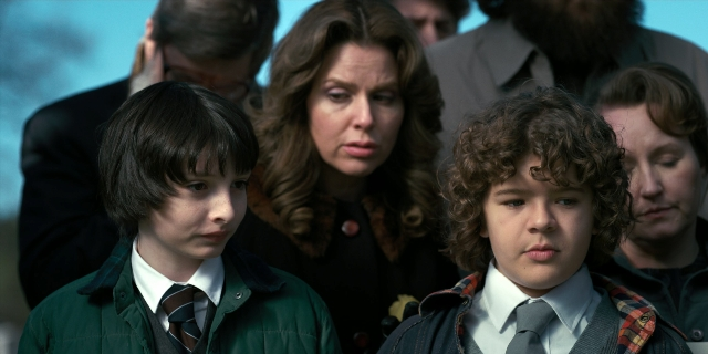 Wide shot frame from Stranger Things — standing, suit, tie