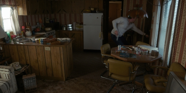 Wide shot frame from Stranger Things — standing, room, table