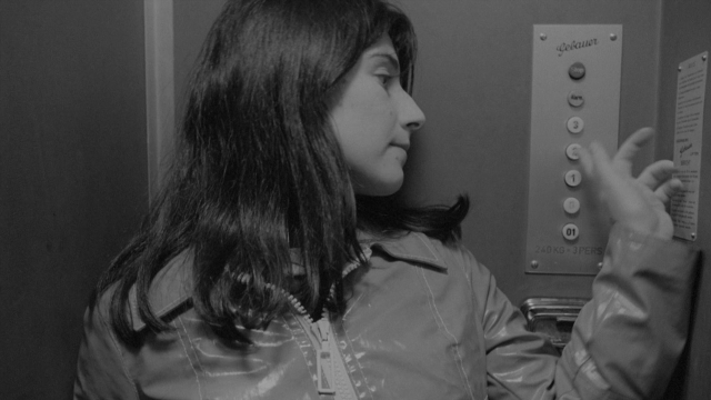Wide shot frame from Je tu il elle — standing, jacket, face