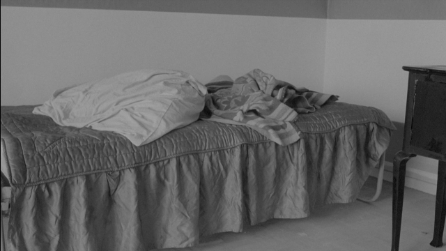 Wide shot frame from Je tu il elle — room, bed, furniture
