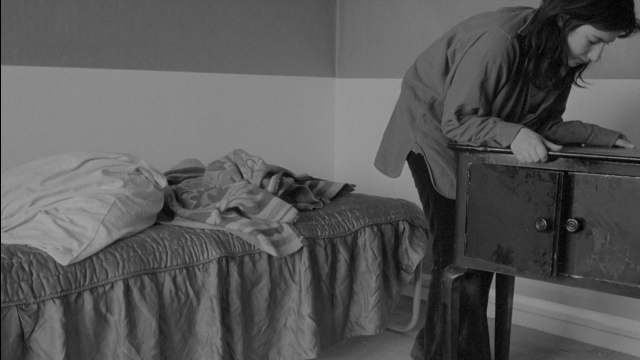 Wide shot frame from Je tu il elle — standing, room, table