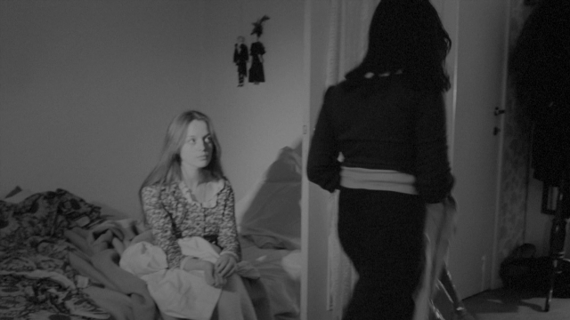 Wide shot frame from Je tu il elle — sitting, standing, room