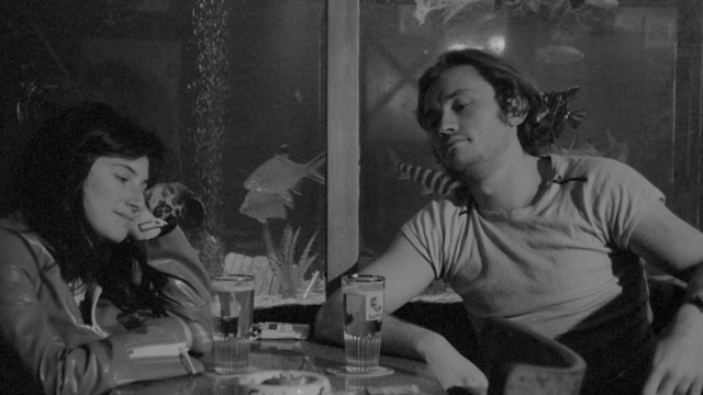 Wide shot frame from Je tu il elle — sitting, table, dialogue