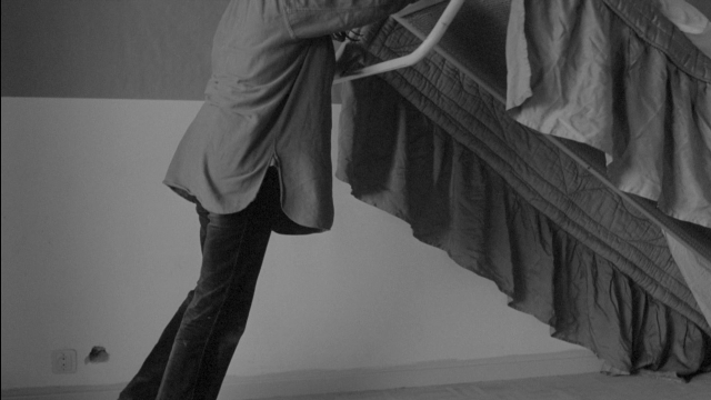 Wide shot frame from Je tu il elle — standing, room, bed