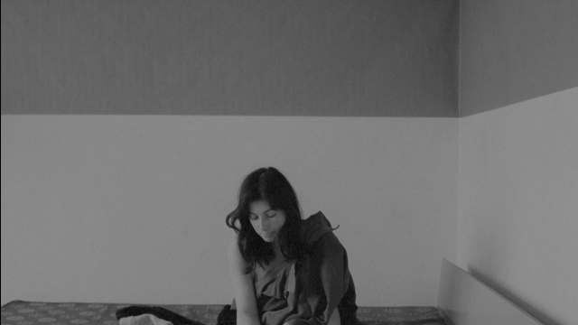 Wide shot frame from Je tu il elle — sitting, bed, phone