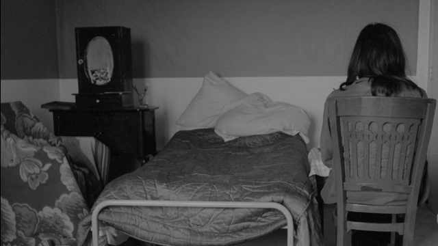 Wide shot frame from Je tu il elle — sitting, room, bed