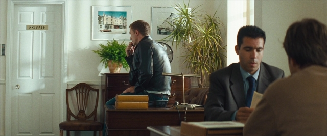 Wide shot frame from Layer Cake — sitting, standing, dialogue