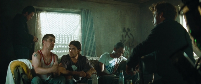 Wide shot frame from Layer Cake — sitting, standing, room