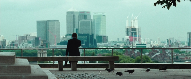 Wide shot frame from Layer Cake — sitting, coat, skyscraper