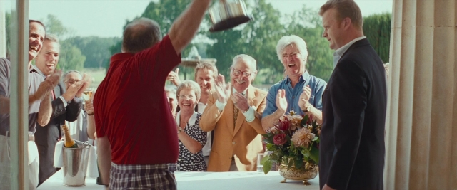Wide shot frame from Layer Cake — standing, table, suit
