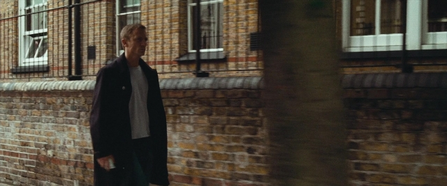 Wide shot frame from Layer Cake — walking, street, coat