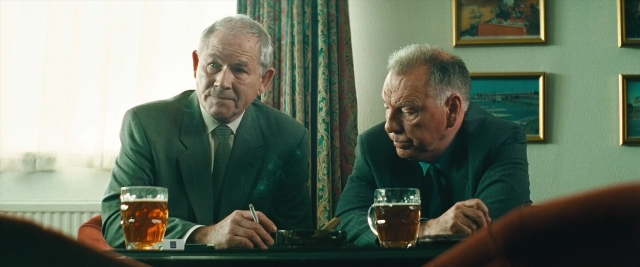 Wide shot frame from Layer Cake — sitting, table, dialogue