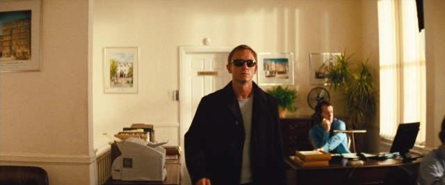 Wide shot frame from Layer Cake — sitting, standing, table