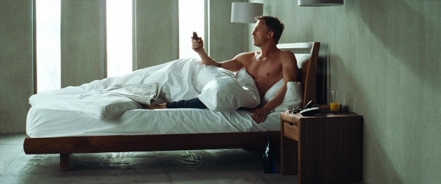 Wide shot frame from Layer Cake — room, bed, phone