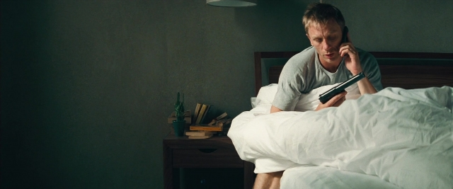 Wide shot frame from Layer Cake — sitting, bed, hand