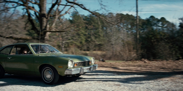 Wide shot frame from Stranger Things — door, street, car