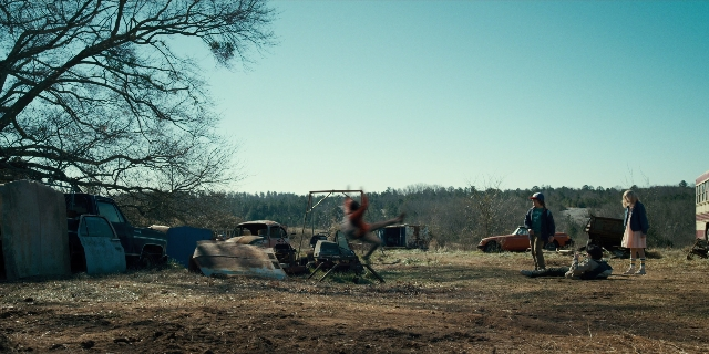 Wide shot frame from Stranger Things — sitting, standing, shirt