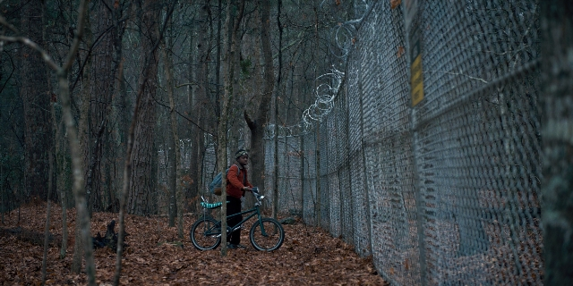 Wide shot frame from Stranger Things — hat, bicycle, forest