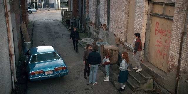 Wide shot frame from Stranger Things — walking, car, person