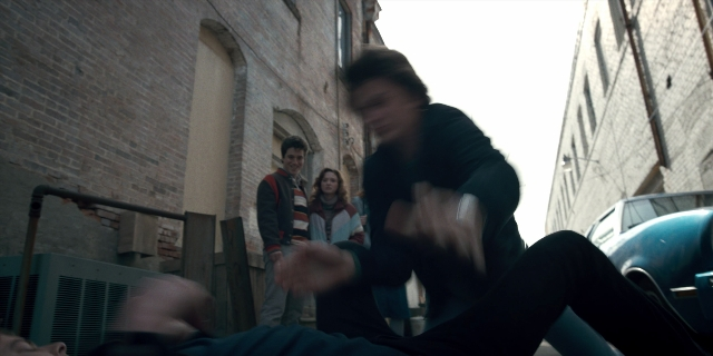 Wide shot frame from Stranger Things — standing, street, car