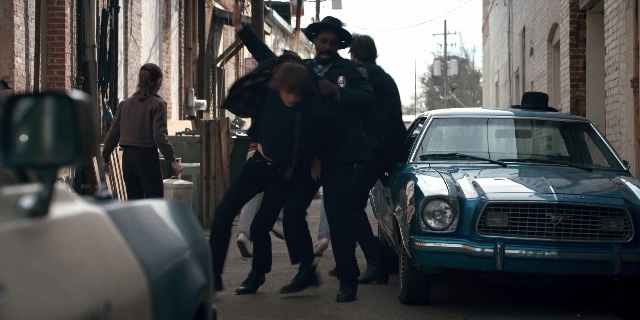 Wide shot frame from Stranger Things — walking, street, hat