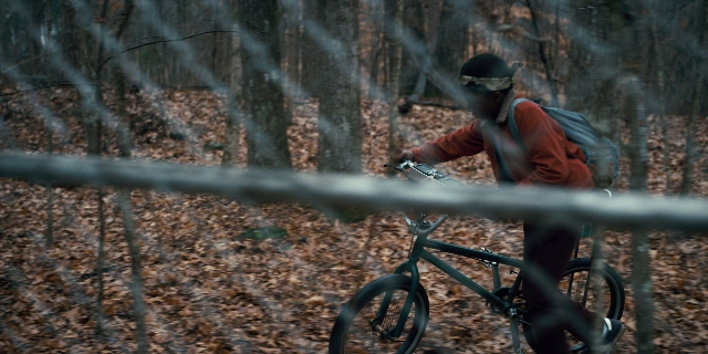 Wide shot frame from Stranger Things — hat, bicycle, forest