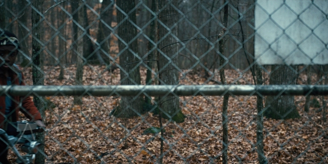 Wide shot frame from Stranger Things — standing, hat, hand