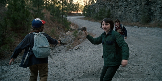 Wide shot frame from Stranger Things — walking, street, hat