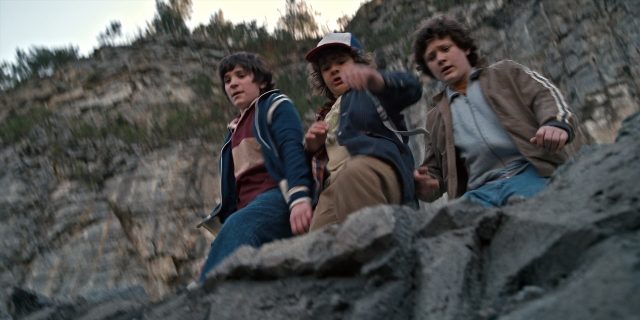 Wide shot frame from Stranger Things — sitting, hat, shirt