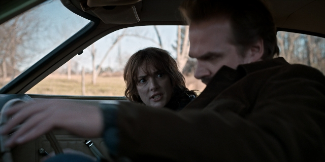 Wide shot frame from Stranger Things — sitting, dialogue, car