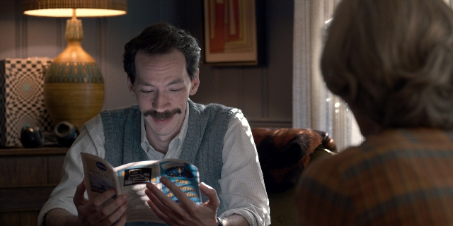 Wide shot frame from Stranger Things — sitting, book, room