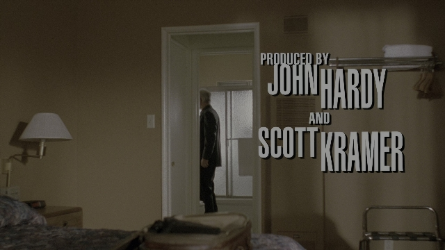 Wide shot frame from The Limey — standing, room, bed