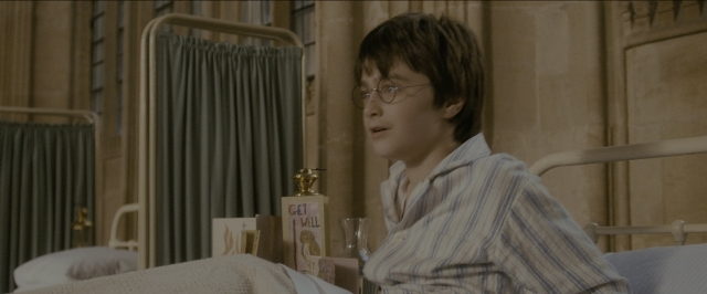 Wide shot frame from Harry Potter and the Sorcerer's Stone — sitting, book, table