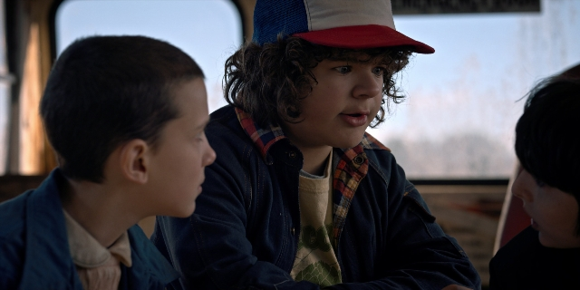 Wide shot frame from Stranger Things — sitting, hat, shirt