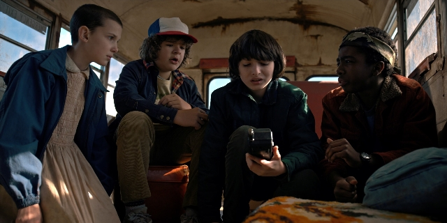 Wide shot frame from Stranger Things — sitting, dialogue, phone